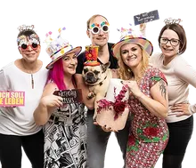 Gruppe mit Partyhüten und Sprechblasen-Requisiten in der Fotobox zum Geburtstag