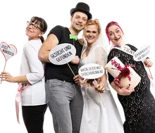 Hochzeitsgesellschaft mit Fotobox-Requisiten, unter anderem einem „Just Married“-Schild