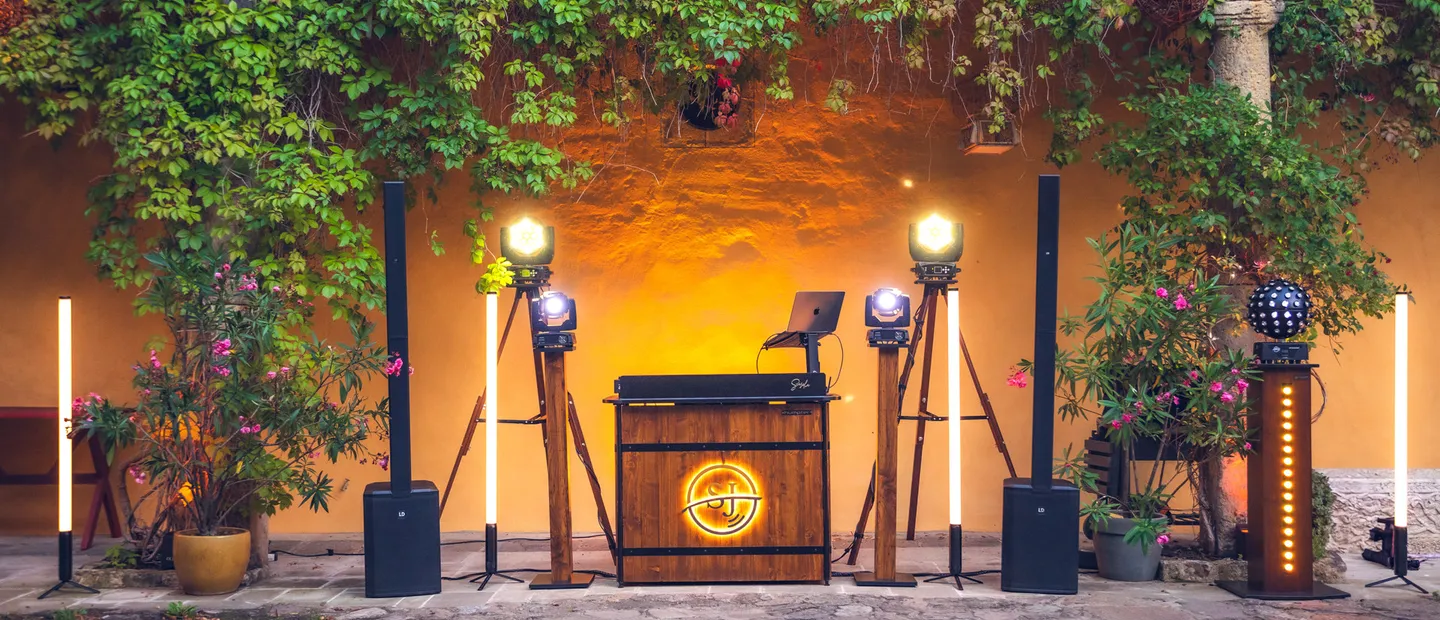 Beleuchtetes DJ-Pult aus Holz mit Ton- und Lichttechnik im Innenhof