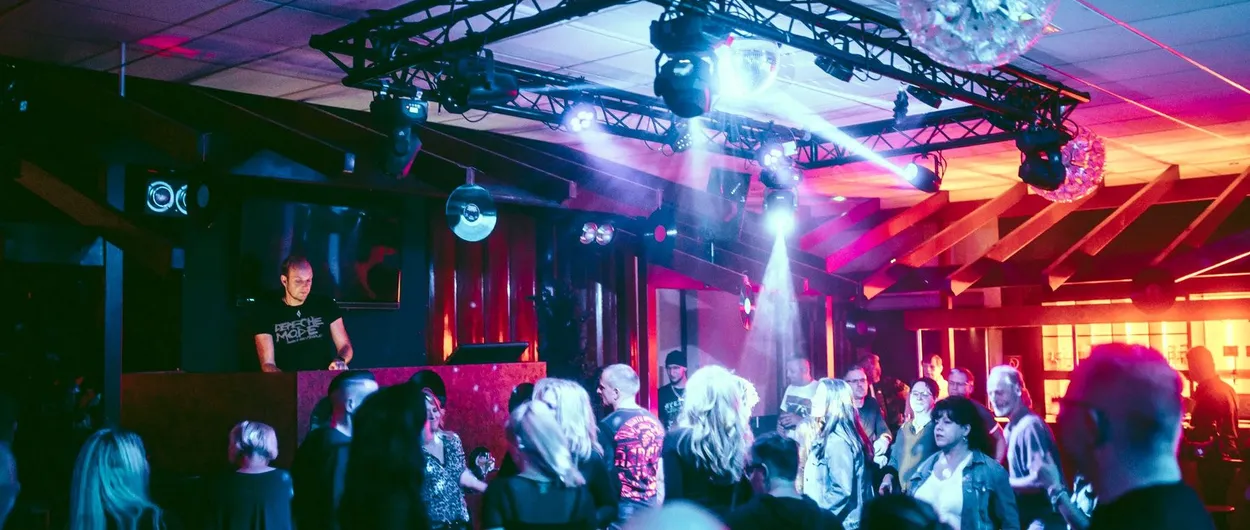 DJ am Pult vor feiernden Gästen auf der Tanzfläche