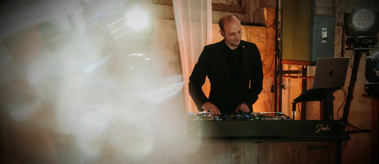 DJ Sascha Juranek am DJ-Pult mit SJ-Logo