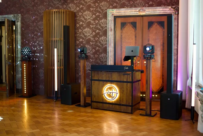 Aufgebautes DJ-Pult mit Ton- und Lichttechnik in einem Saal mit Parkett und historischer Tapete