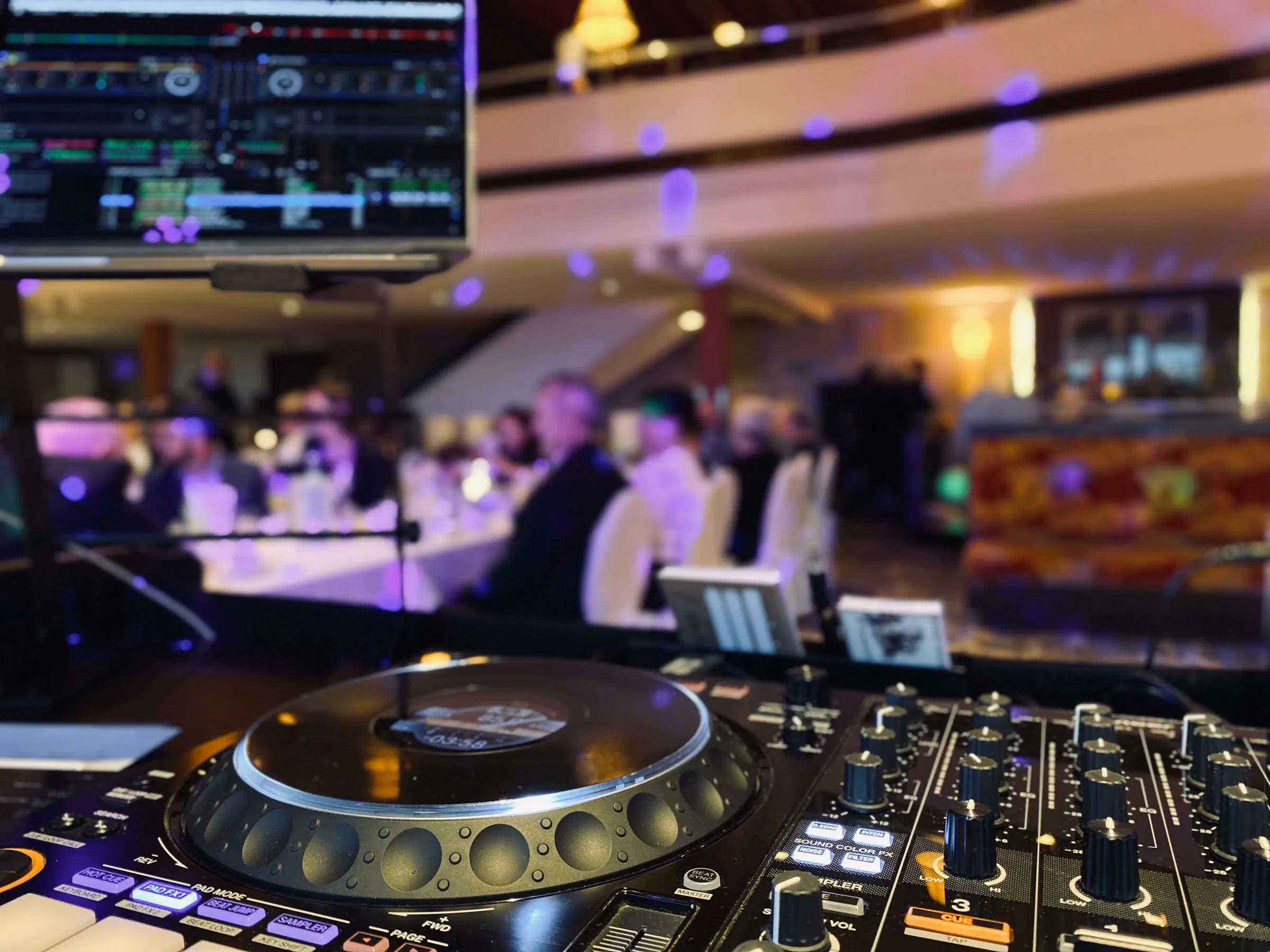 DJ-Technik im Vordergrund, Gäste an den Tafeln dahinter