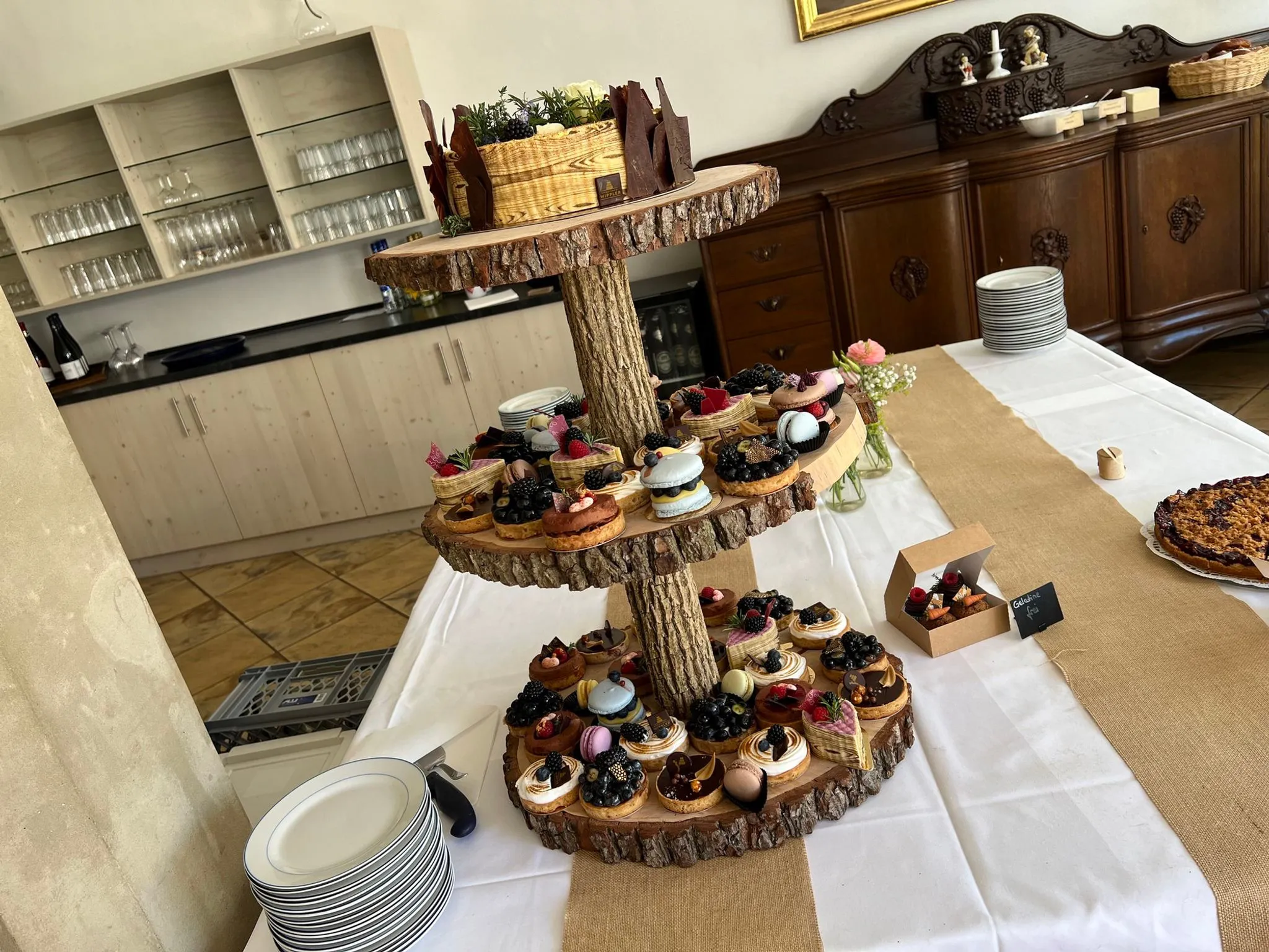 Etagere aus Baumscheiben mit Torte und kleinen Törtchen
