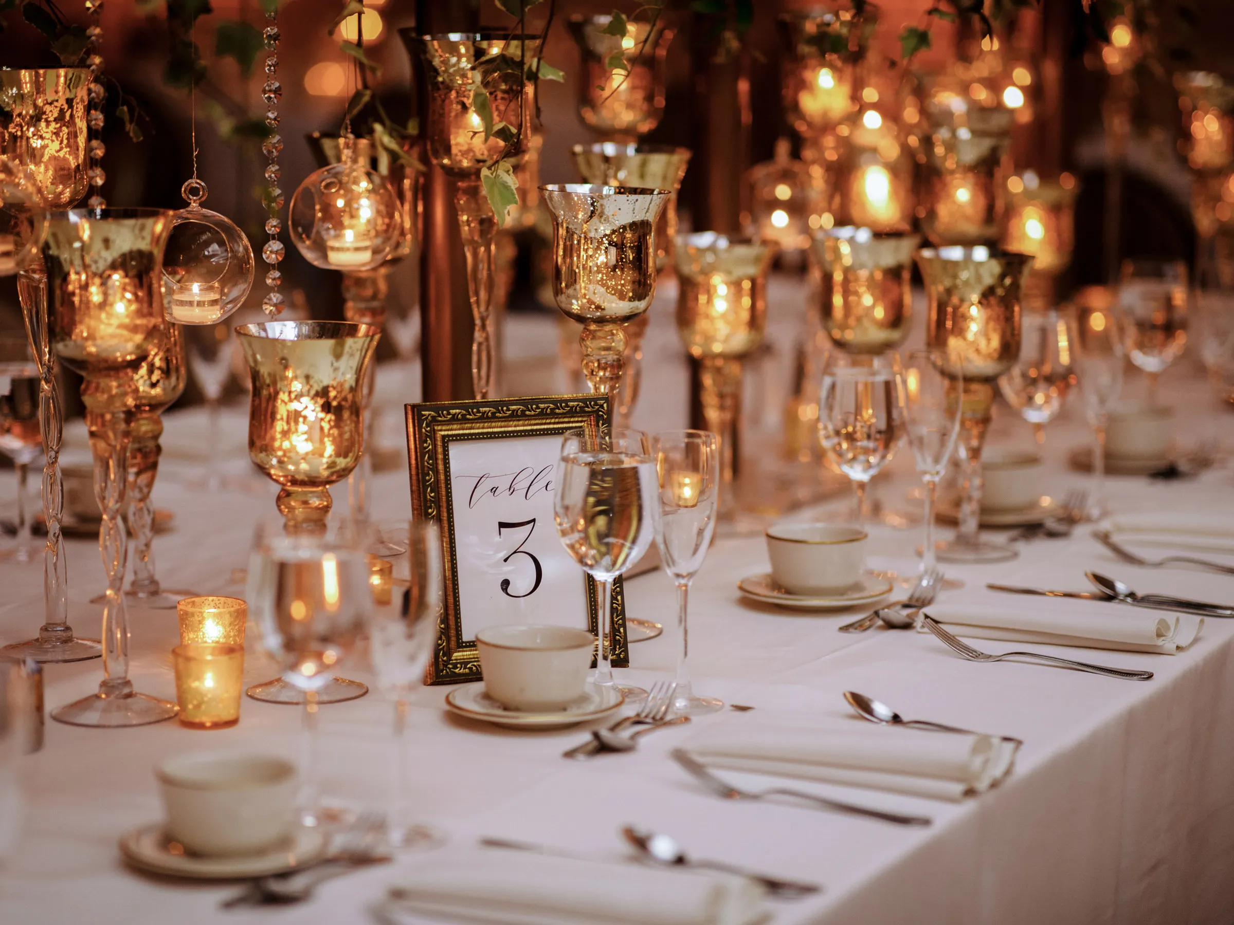Festlich gedeckte Hochzeitstafel mit goldenen Kerzengläsern