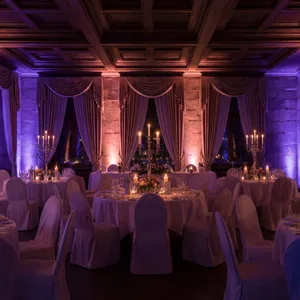 Festsaal mit gedeckten Tischen und Kerzen in violettem Ambientelicht