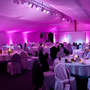 Festzelt mit Ambientelicht in Pink, eingedeckte Tische mit Stuhlhussen