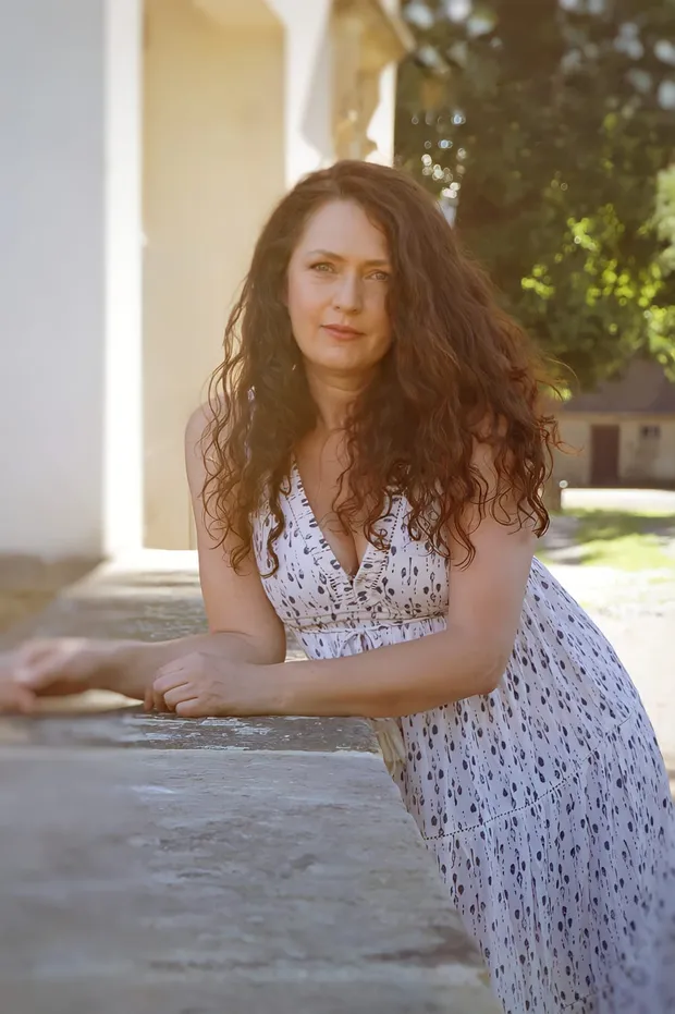 Frau im gemusterten Sommerkleid vor einem historischen Gebäude