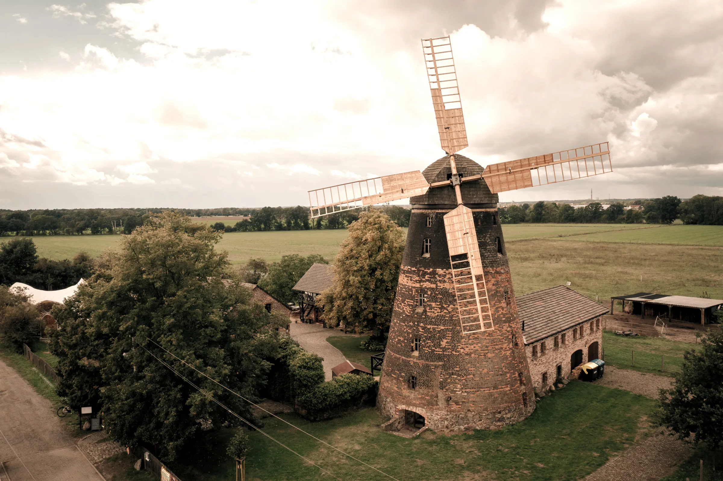 Historische Holländerwindmühle mit Nebengebäuden vor weiten Feldern