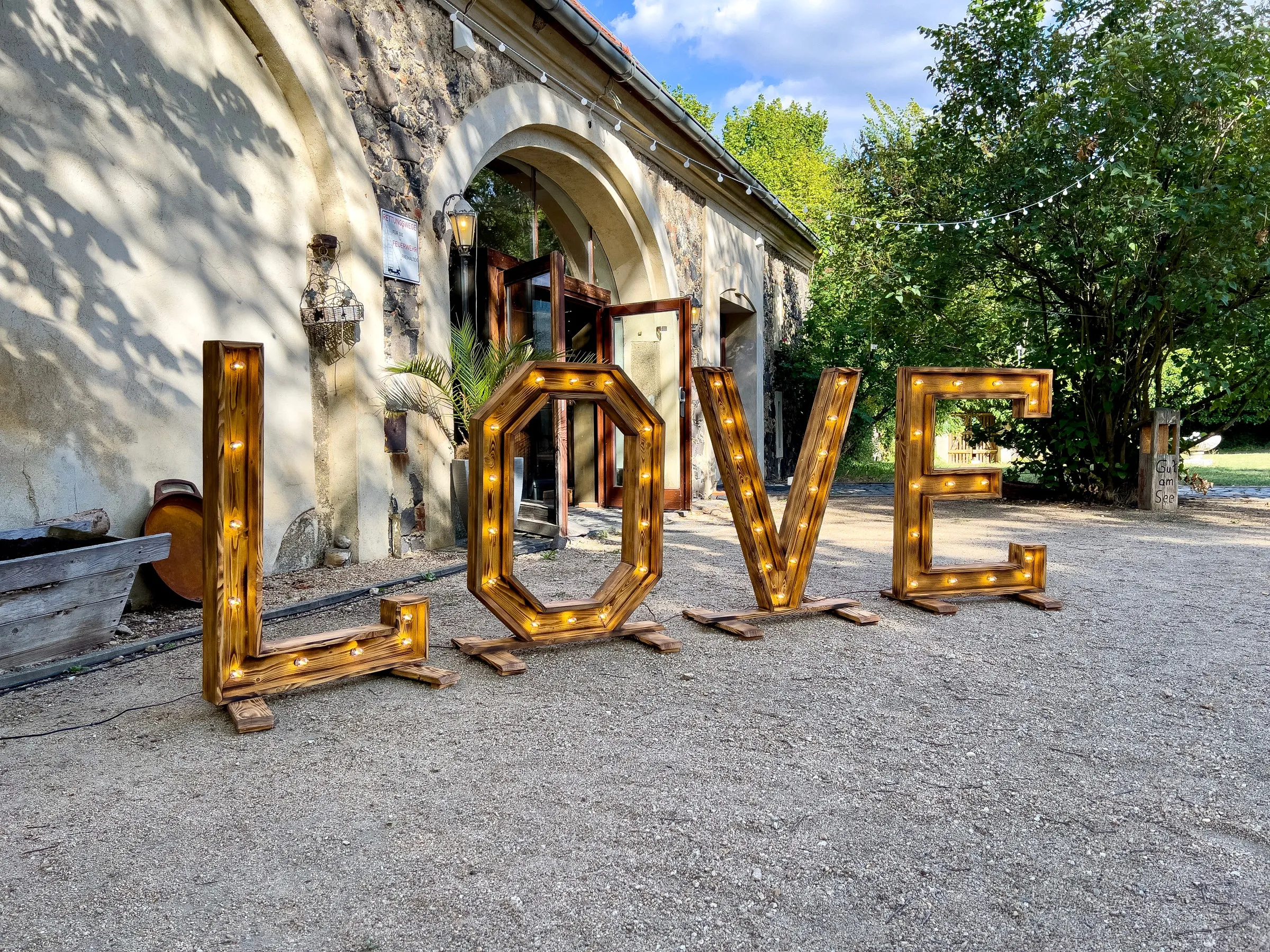 Beleuchtete LOVE-Buchstaben aus Holz vor einem Gebäude