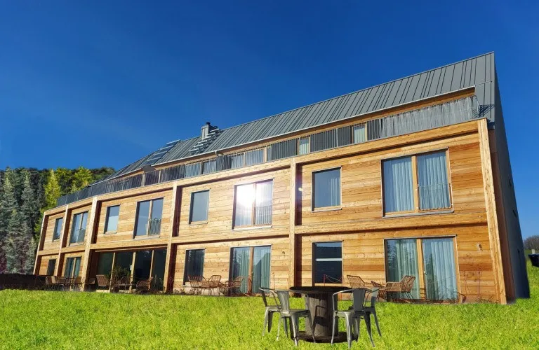 Holzverkleidetes Gebäude der Ferienapartments auf grüner Wiese