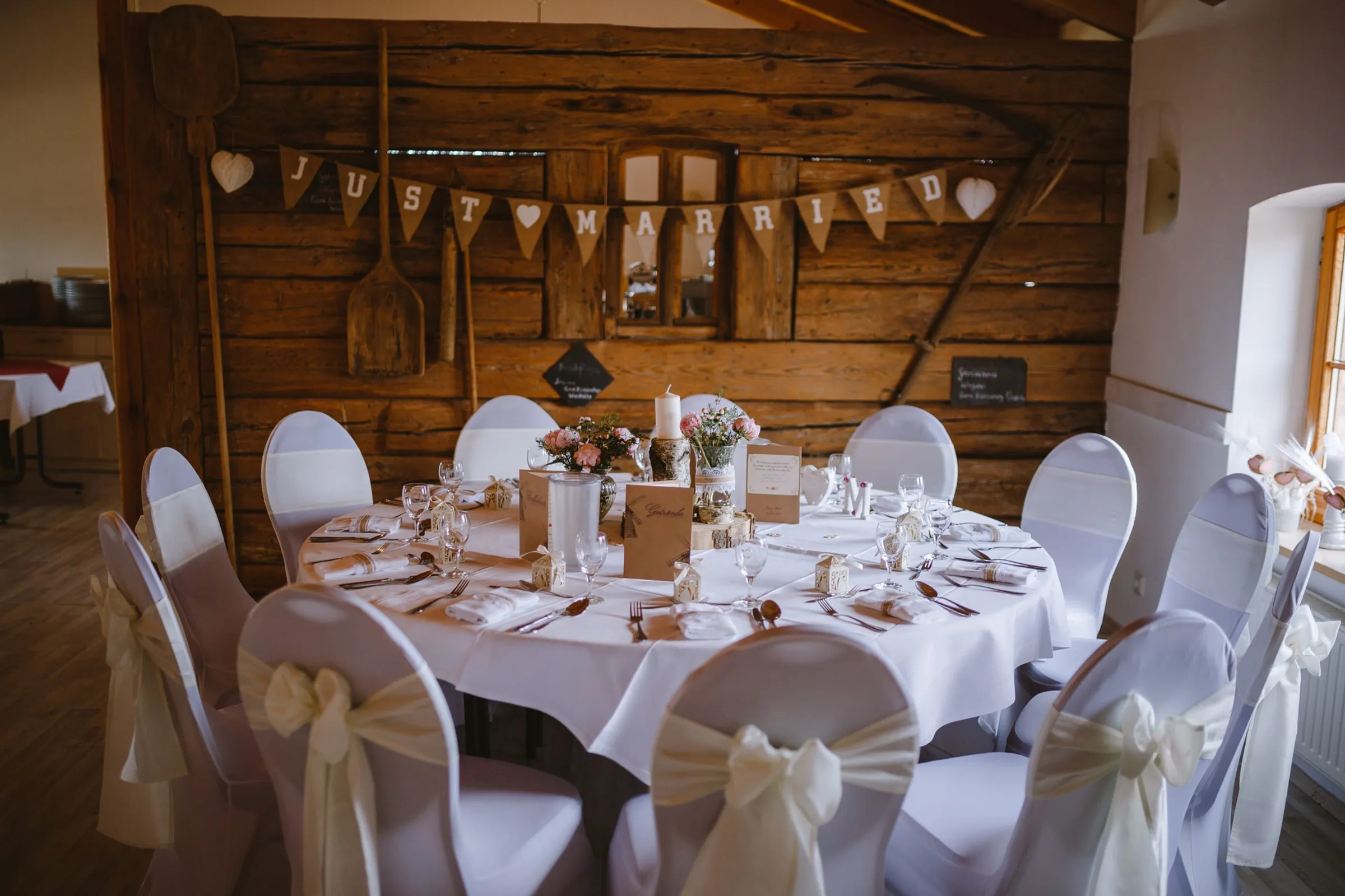 Runde Hochzeitstafel vor Holzwand mit Just-Married-Wimpelkette