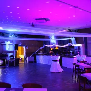 Saal mit Ambientelicht in Lila und Blau, DJ-Technik und Discokugel im Vordergrund