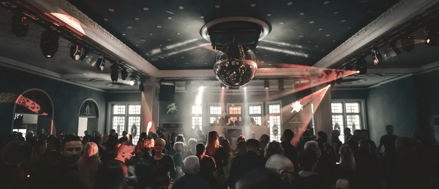 Feiernde Gäste unter einer Discokugel im festlichen Saal