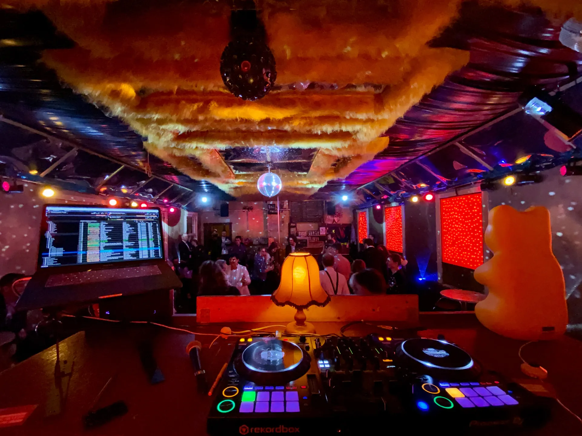Tanzsaal mit Discokugeln, roten Lichtflächen und feiernden Gästen