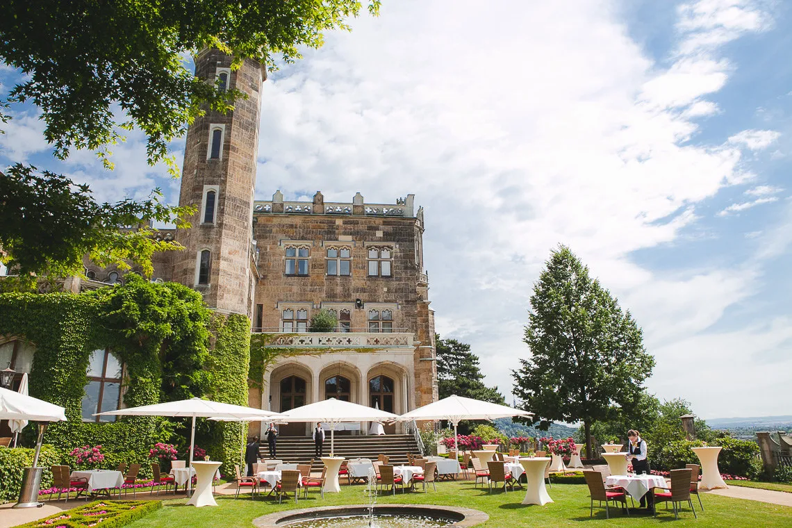 Terrasse mit Stehtischen und Sonnenschirmen vor dem Schlossturm